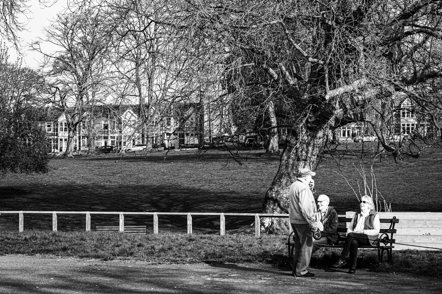 Group of three elderly people chatting by a park bench